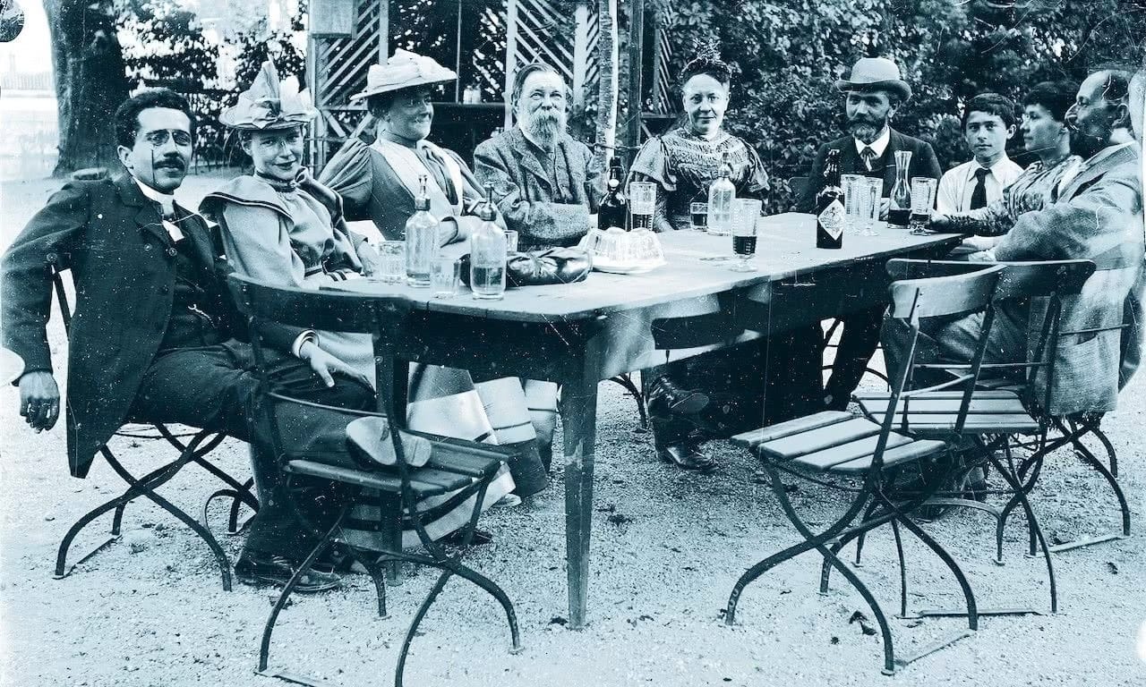 Clara Zetkin (third from left) at a table with Friedrich Engels (to her left), and August Bebel (man with hat) at Zürich International Socialist Workers' Congress in 1893. Source: Wikimedia Commons.
